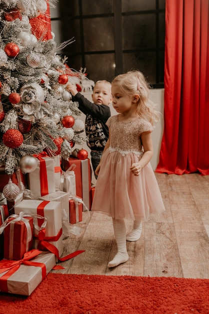 Famiglia felice con bambino che celebra il nuovo anno e il natale all'albero di natale decorato e alle ghirlande