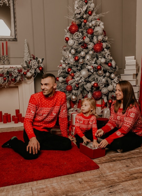 Happy family with child celebrating New Year and Christmas at decorated Christmas tree and garlands