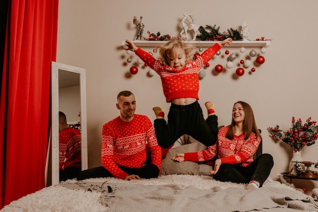 Foto famiglia felice con bambino che celebra il nuovo anno e il natale all'albero di natale decorato e alle ghirlande