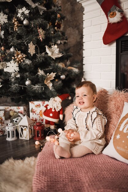 Happy family with child celebrating New Year and Christmas at decorated Christmas tree and garlands