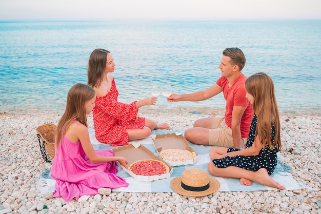 Famiglia felice con bambini sulla spiaggia picnic