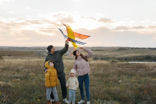 A happy family with children flies a kite and spends time together outdoors in a nature reserve Happy childhood and family holidays Freedom and space