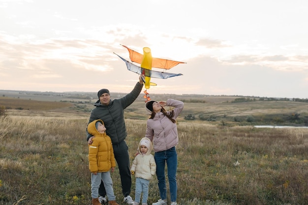 A happy family with children flies a kite and spends time together outdoors in a nature reserve Happy childhood and family holidays Freedom and space