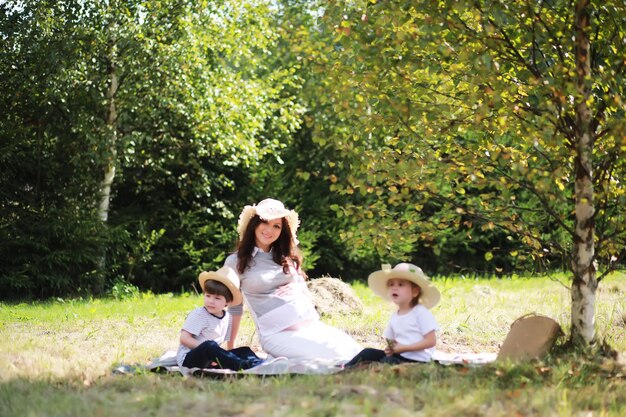 Famiglia felice con bambini che fanno picnic nel parco, genitori con bambini seduti sull'erba del giardino e che mangiano anguria all'aperto