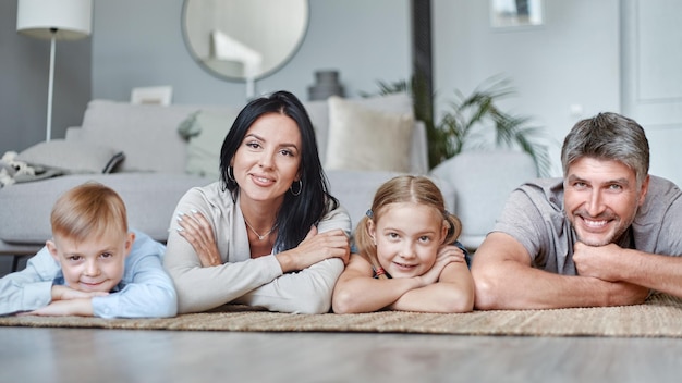 Famiglia felice con bambini sdraiati sul pavimento nel soggiorno