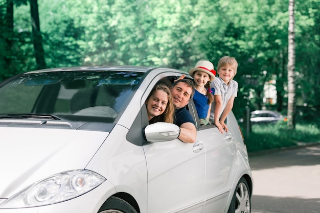 Famiglia felice con bambini seduti in una macchina di famiglia