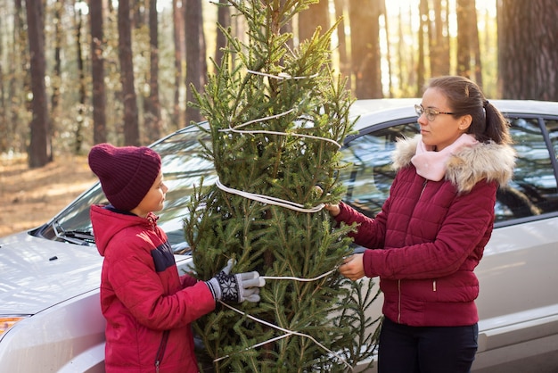 Happy family with christmas tree standing near the car
