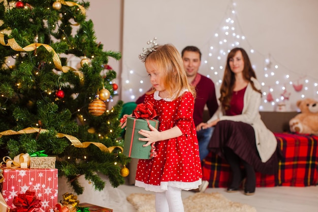 Happy family with daughter decorate the Christmas tree. Holiday evening