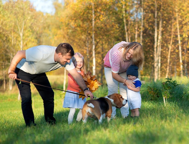 秋の草の上で犬と幸せな家族