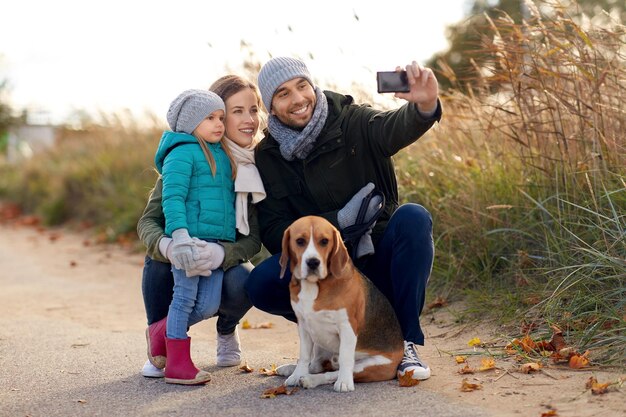 Foto famiglia felice con il cane che si fa un selfie in autunno