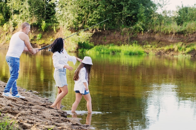 Famiglia felice con la canna da pesca sul fiume estivo