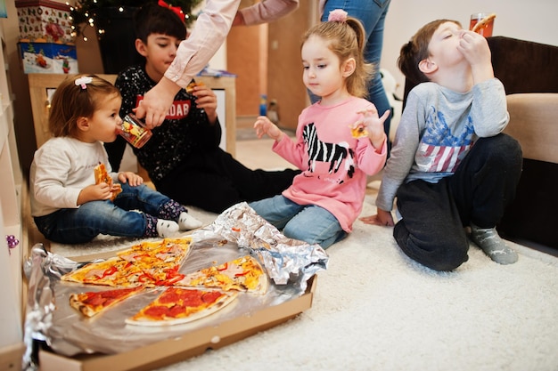 Happy family with four kids eating pizza at home.