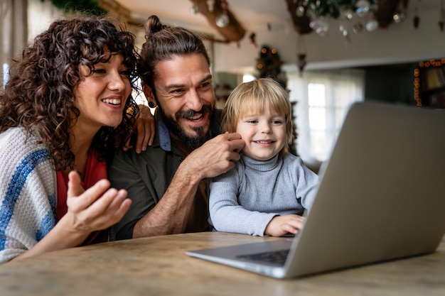 Photo happy family with kid having fun using laptop together, watching internet video, making online call at home