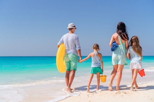 Happy family with kids walk on the beach at sunset