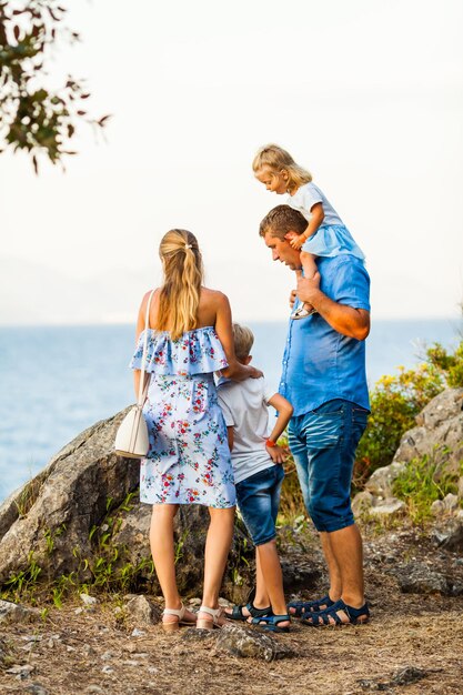 happy family with kids walk at sunset rocks and look on the sea