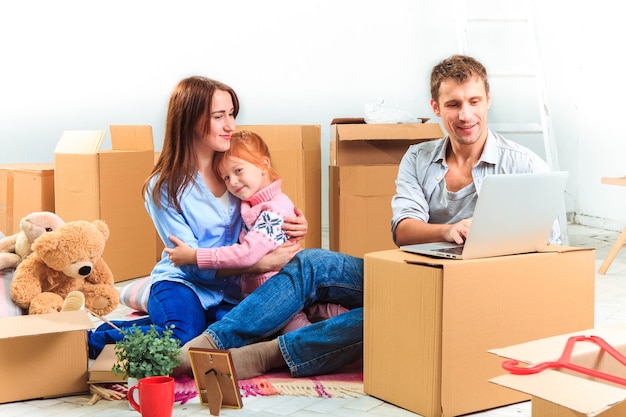 The happy family with laptop at repair and relocation on a background of boxes