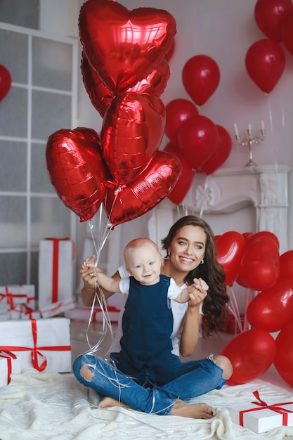 Happy family with little baby boys in festive atmosphere on background of balloons and gift boxes