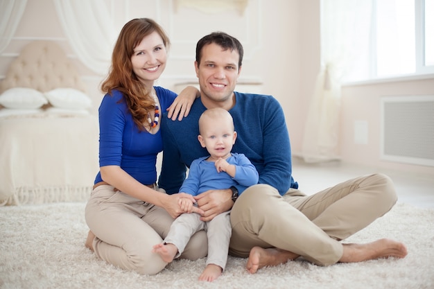 Famiglia felice con il piccolo bambino che gioca sul tappeto