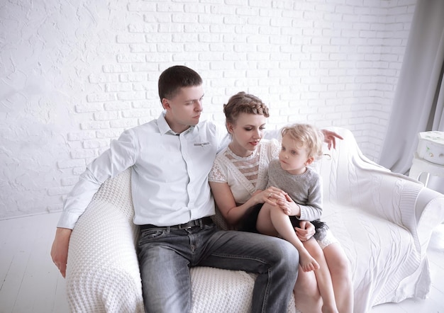 Happy family with little daughter sitting on sofa