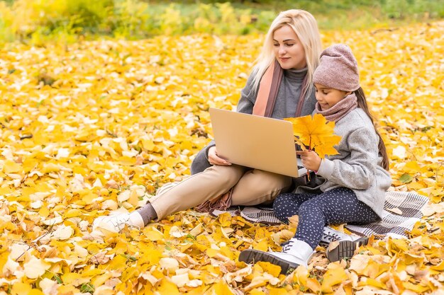 Happy family with little daughter smiling happily looking at laptop screen walking in park