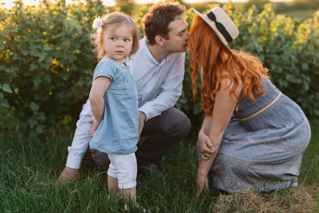 Foto famiglia felice con la piccola figlia che passa insieme tempo nel campo soleggiato