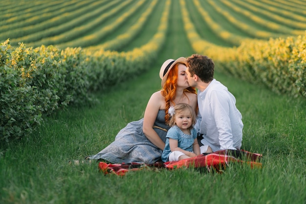 Happy family with little daughter spending time together in the sunny field