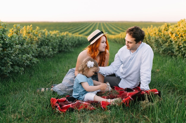 Happy family with little daughter spending time together in the sunny field