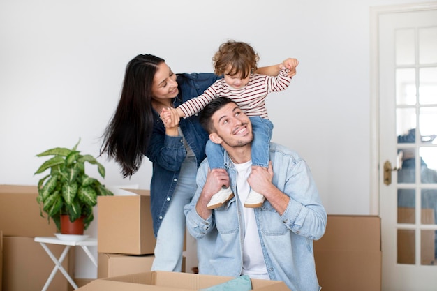 Happy family with little son having fun in new home after moving