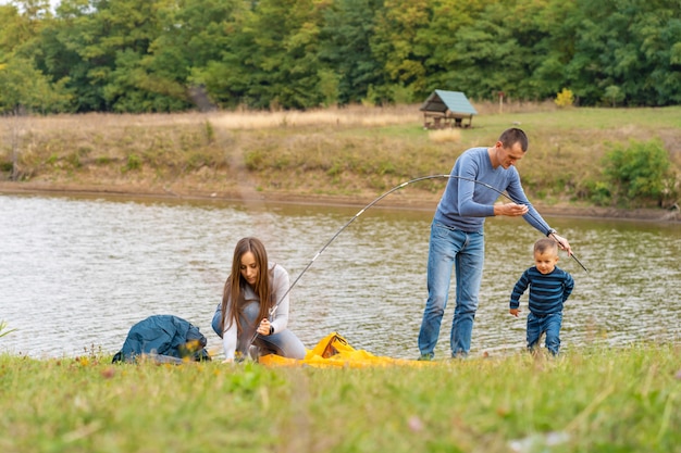 Happy family with little son set up camping tent. Happy childhood, camping trip with parents. A child helps to set up a tent