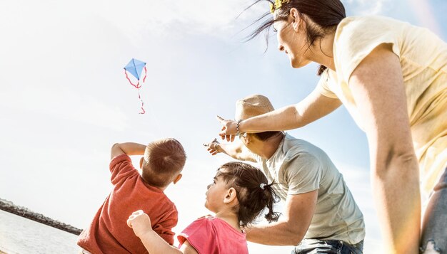 Happy family with parents and children playing together with kite at beach vacation