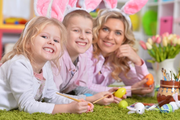 イースターと色の卵の準備をしているウサギの耳を持つ幸せな家族。