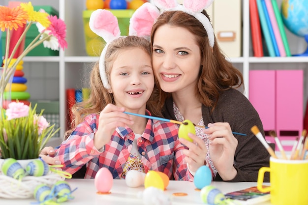 Happy family with rabbit ears preparing for Easter and color eggs