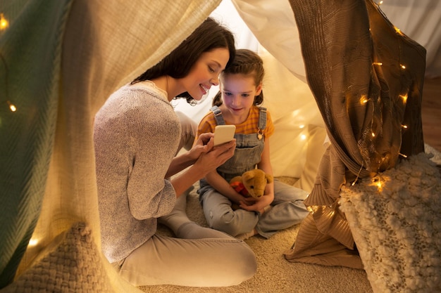 Photo happy family with smartphone in kids tent at home