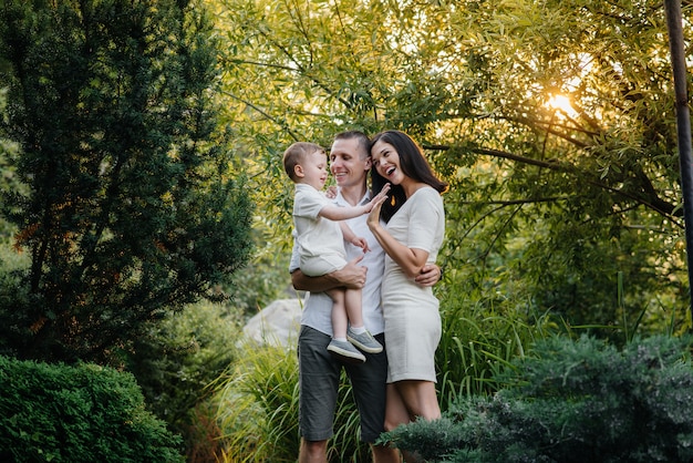 Famiglia felice con il loro figlio che cammina nel parco al tramonto. felicità. amore