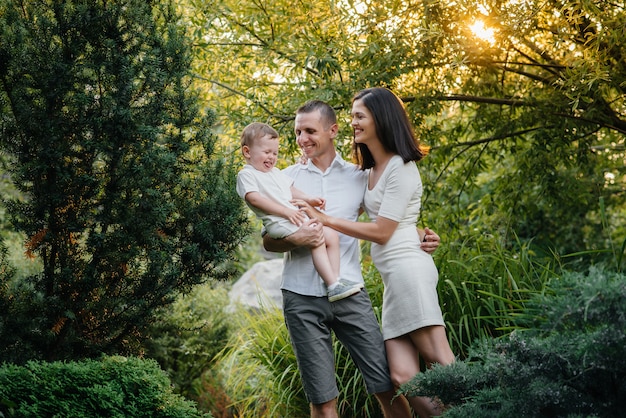 Foto famiglia felice con il loro figlio che cammina nel parco al tramonto. felicità. amore