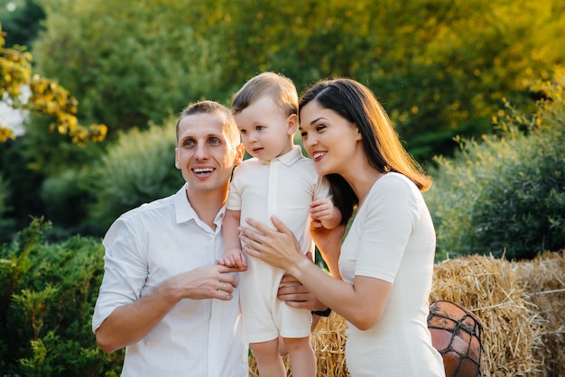 Famiglia felice con il loro figlio che cammina nel parco al tramonto. felicità. amore