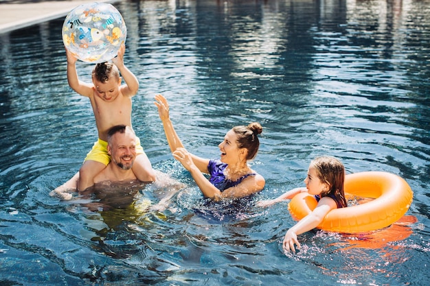 Famiglia felice con due bambini che si divertono in piscina concetto di vacanza estiva