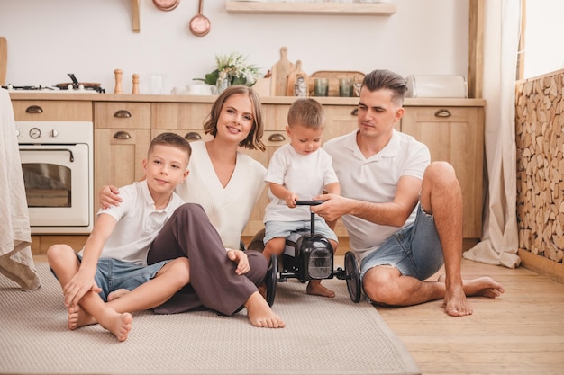 La famiglia felice con due figli si siede sul pavimento in cucina