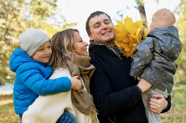 Happy family with two young children in a beautiful autumn park. Love, tenderness and warm relations in the family.