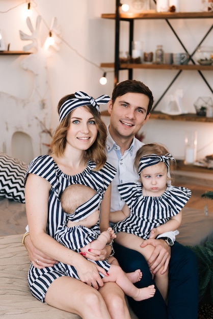 Happy family with young parents and two beautiful girls. Cute family portrait in a beautiful interior