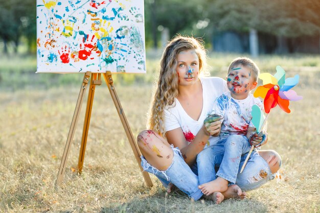 Famiglia felice. giovane madre graziosa divertendosi con i suoi bambini all'aperto. pittura di famiglia