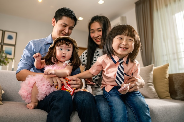 Happy familyChildren are sitting on the parents lap on the sofa in the living room 
Children