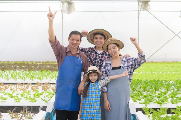 A happy farmer family working in hydroponic greenhouse farm clean food and healthy eating concept