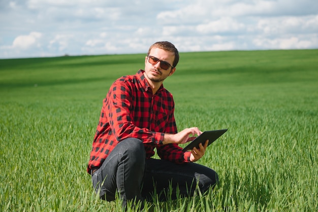 Happy farmer in the fields with a laptop computer