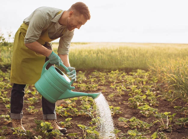 Happy farmer man waters the beds and works in the garden