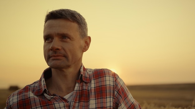 Happy farmer standing in wheat field at golden sunset hour Agronomist portrait