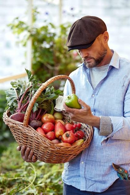 Agricoltore felice con un cesto pieno di verdure di stagione