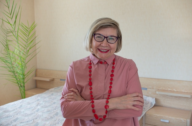 Happy fashionable senior woman gray hair senior woman, middle aged maturesmiling old woman wearing beads on a light background, positive lonely pensioner senior woman