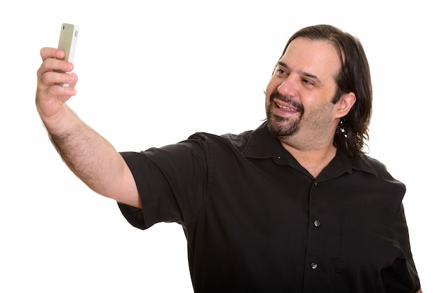 Happy fat bearded Caucasian man smiling while taking selfie with mobile phone