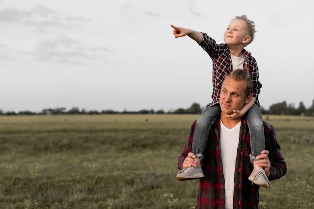 Un padre felice porta un figlio sulle spalle.